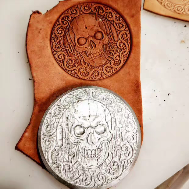 Ornate skull metal stamp with filigree pattern and leather impression
